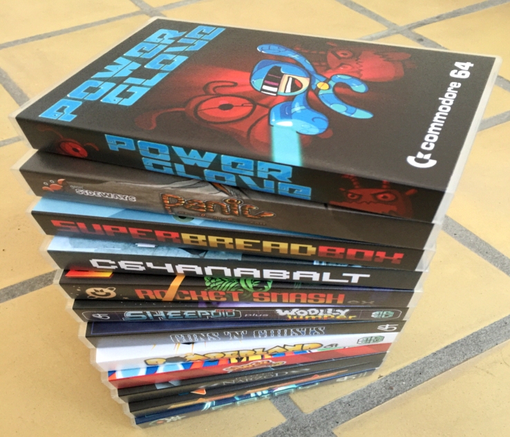 Stack of Commodore 64 cartridge games released by rgcd.co.uk. The list of games includes Power Glove, Rocket Smash EX, Super Bread Box, Bomberland 64, Guns 'n' Ghosts, C64anabalt, Panic Analogue, Fortress of Narzod, Edge Grinder, Fairy Well, UWOL quest for money, Sheepoid DX and Wolly Jumper. Look out for game reviews on breadbox64.com